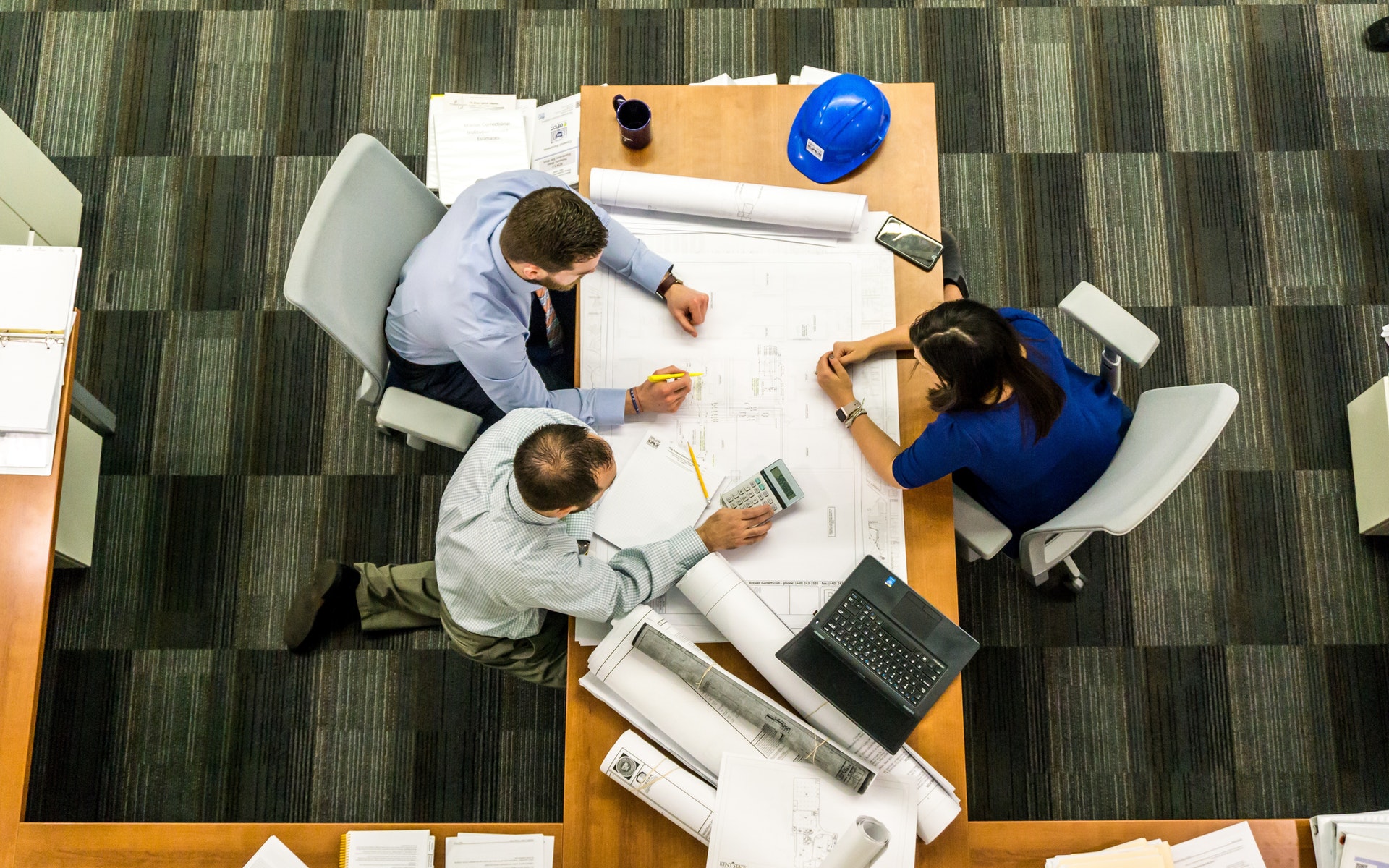 Workers huddle around table with plan sketch.