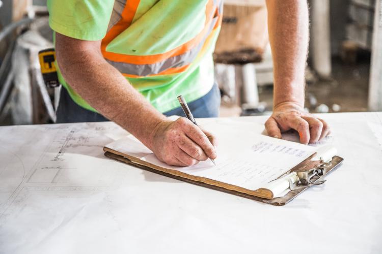 man in a high visibility vest writing on a clipboard