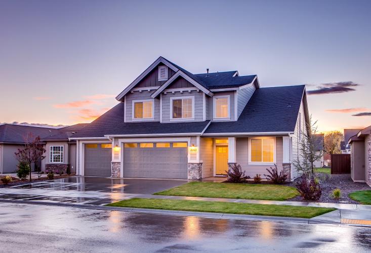 A blue and grey two story house with warm light inside