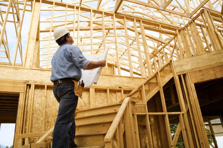 Construction worker assesses building structure.