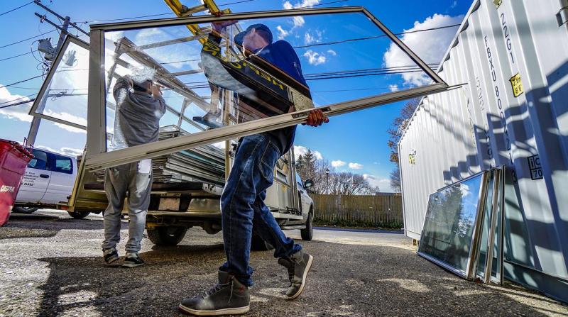 Man carrying glass window to truck